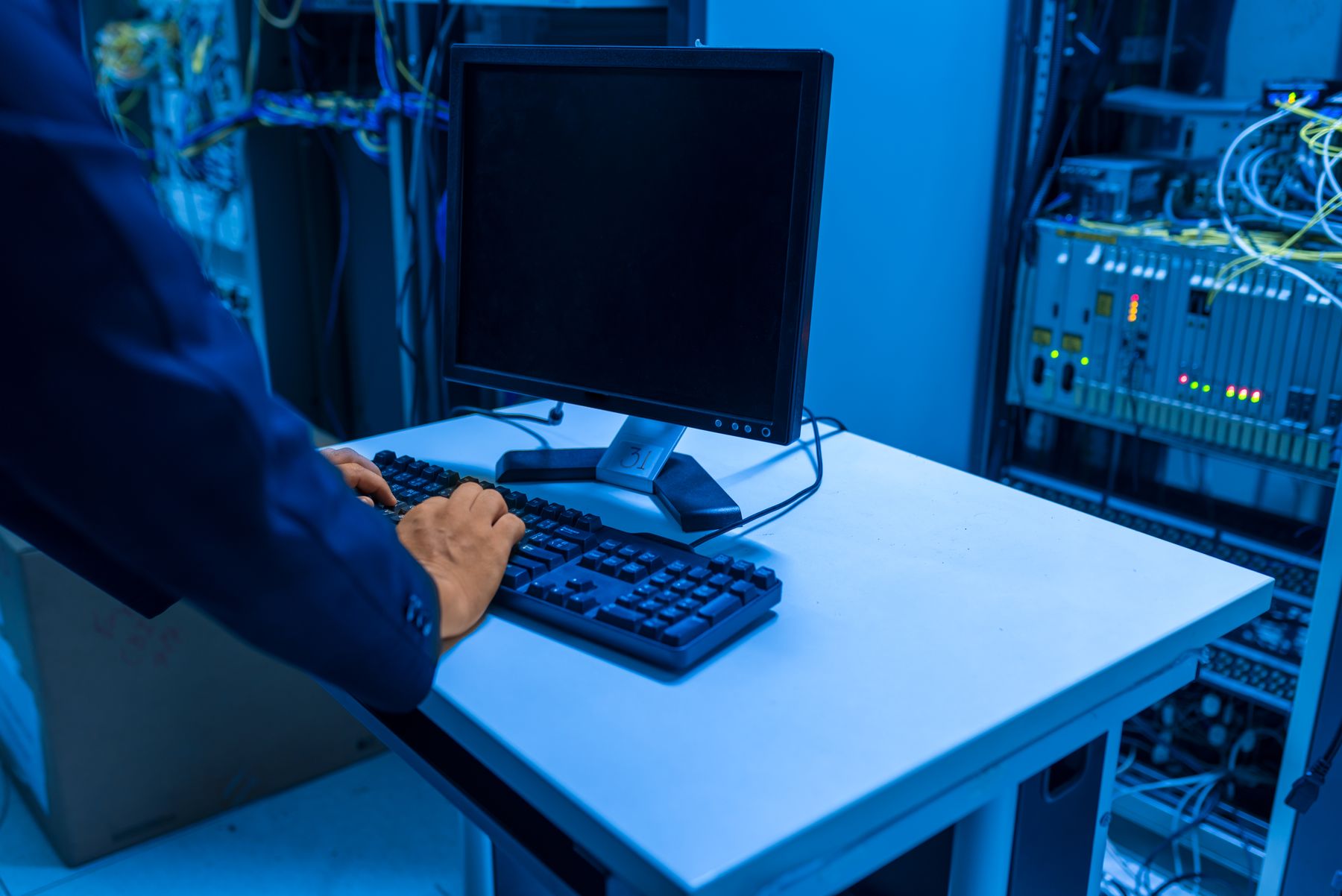 Technology support specialist assisting a colleague at a workstation